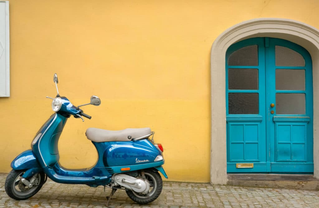 Blaues Mofa, das vor einem gelben Haus steht