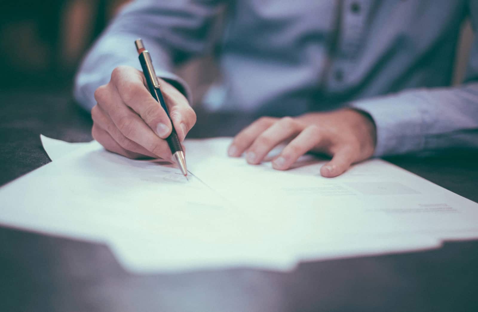 Ein Mann, der einige Dokumente vor sich liegen hat und etwas aufschreibt.